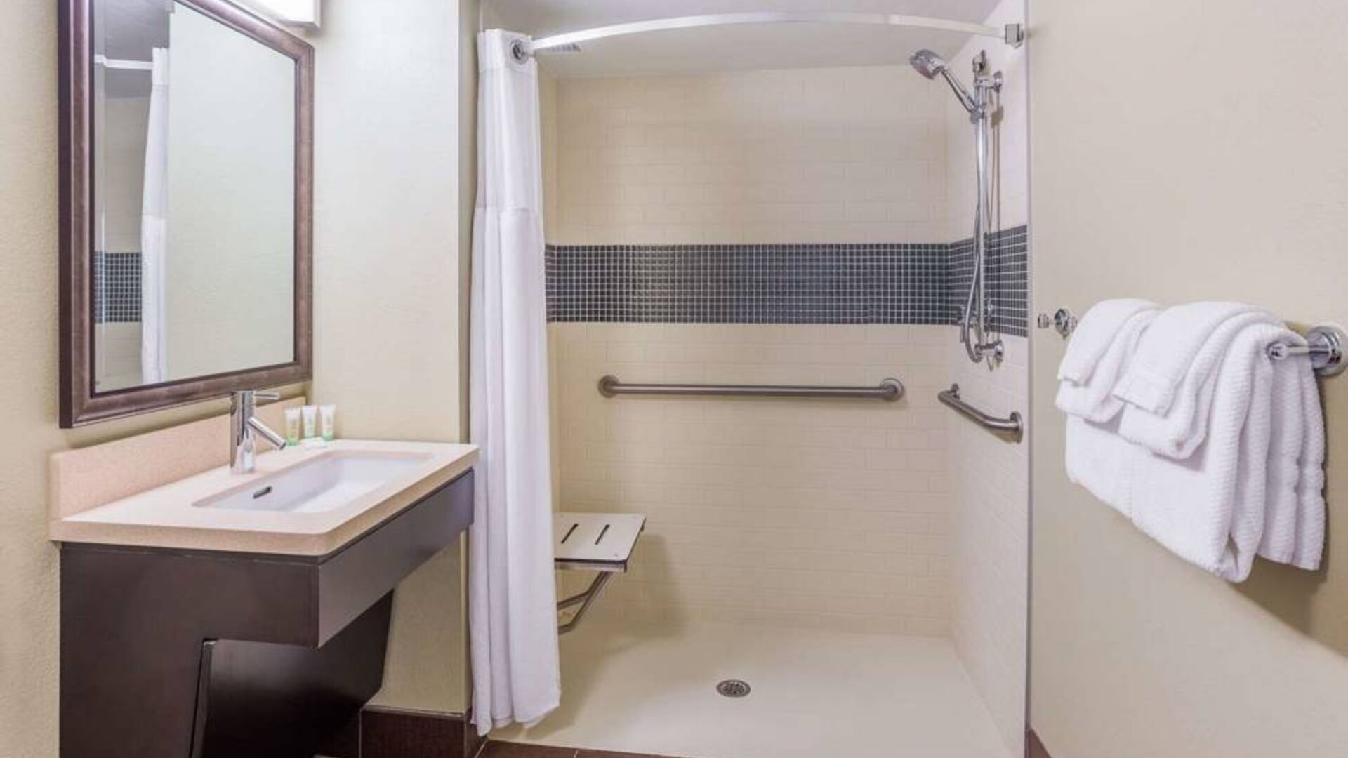 Guest bathroom in Sonesta ES Suites Atlanta Alpharetta Avalon featuring shower with curtain, mirror, and sink.