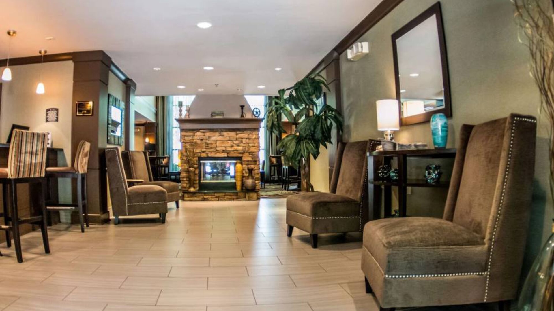 Sonesta ES Suites Atlanta Alpharetta Avalon’s common area lounge is furnished with comfortable seating, potted plants, and a fireplace.