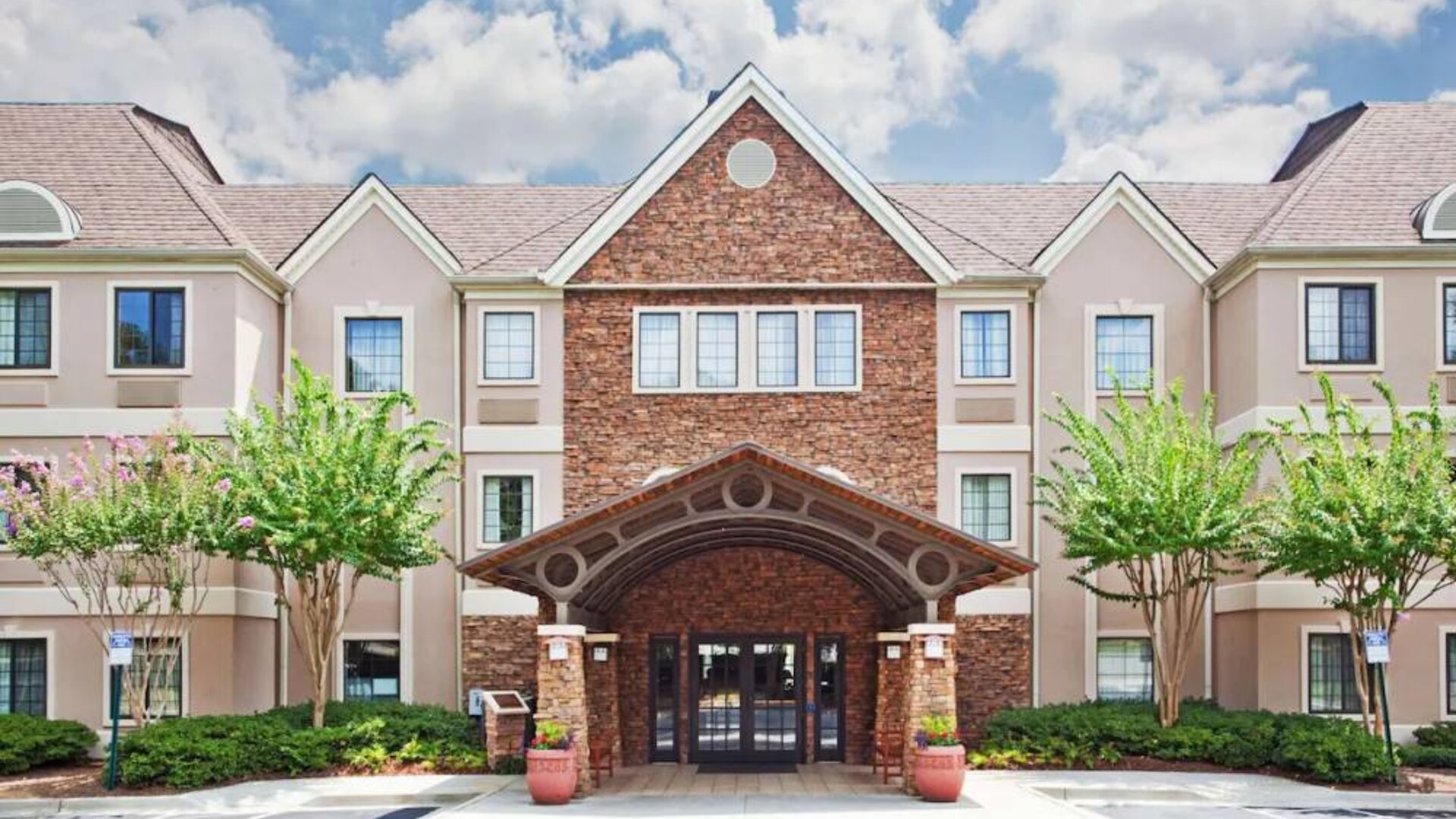 The hotel’s exterior has a brickwork entranceway which is under cover, as are the two nearby benches, with pleasant greenery flanking the front door.