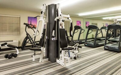 Sonesta Simply Suites Detroit Troy’s fitness center includes free weights, a mirrored wall, and various types of exercise machine.