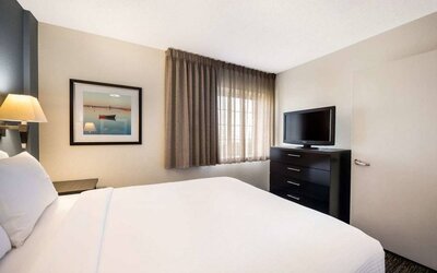 Double bed guest room in Sonesta Simply Suites Parsippany Morris Plains, featuring art on the wall, window, and a television.