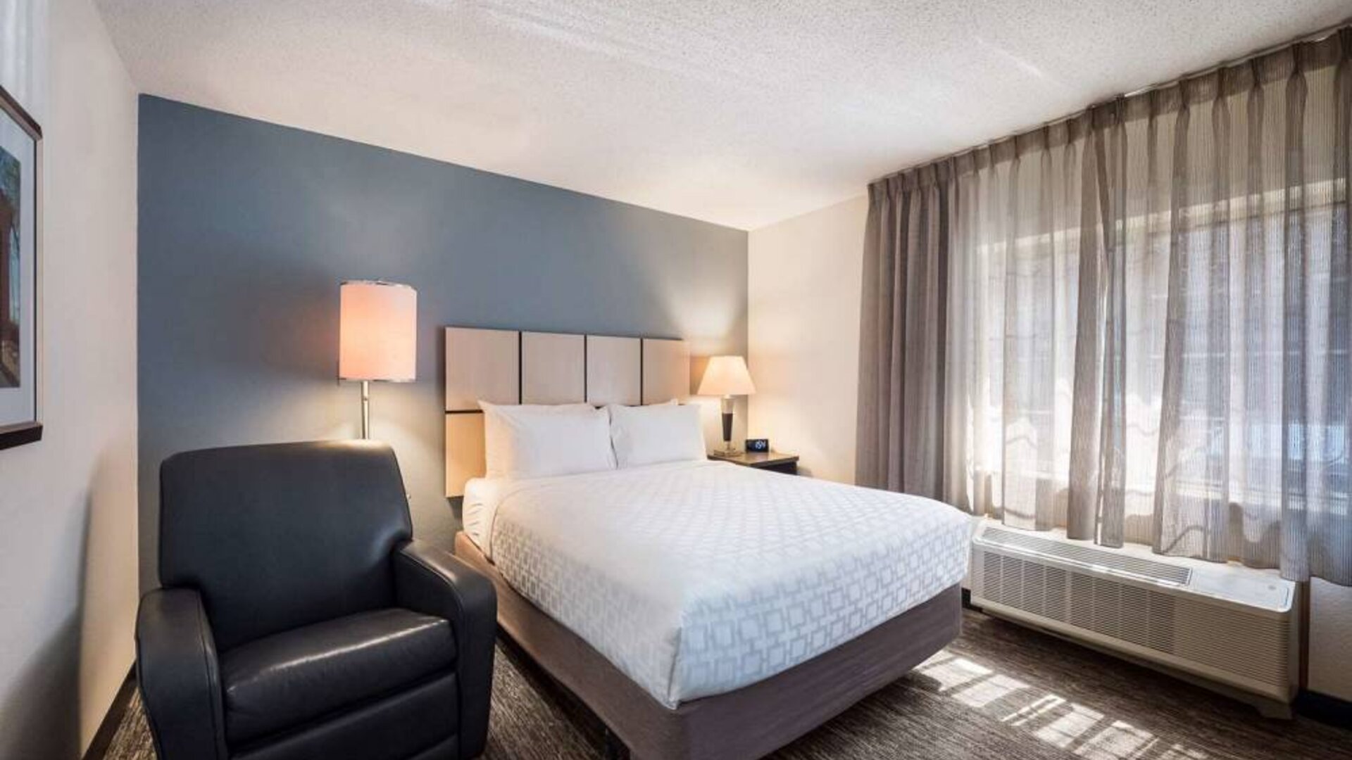 Sonesta Simply Suites Parsippany Morris Plains double bed guest room, with armchair and window.