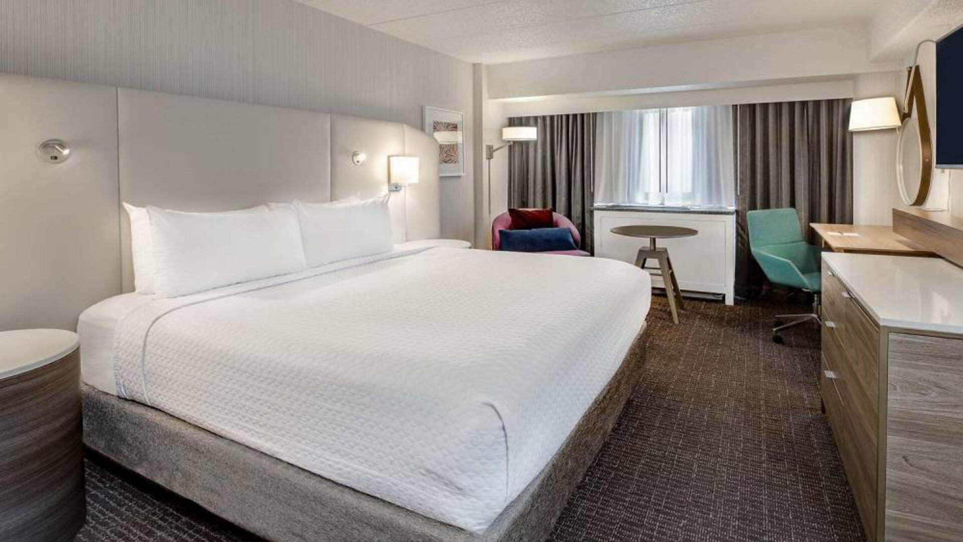 Sonesta Columbus Downtown double bed guest room, featuring armchair, window, and TV, and a workspace desk and chair.