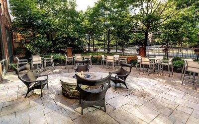 Sonesta Columbus Downtown’s patio features a fire pit that is surrounded by chairs with more tables and chairs nearby.