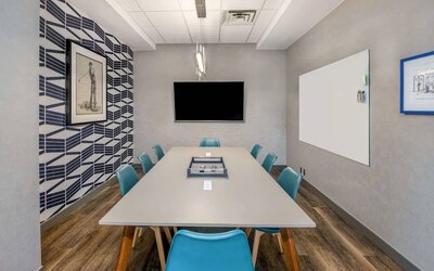 Sonesta Columbus Downtown meeting room, featuring whiteboard and wall-mounted TV, plus a long table and eight chairs.