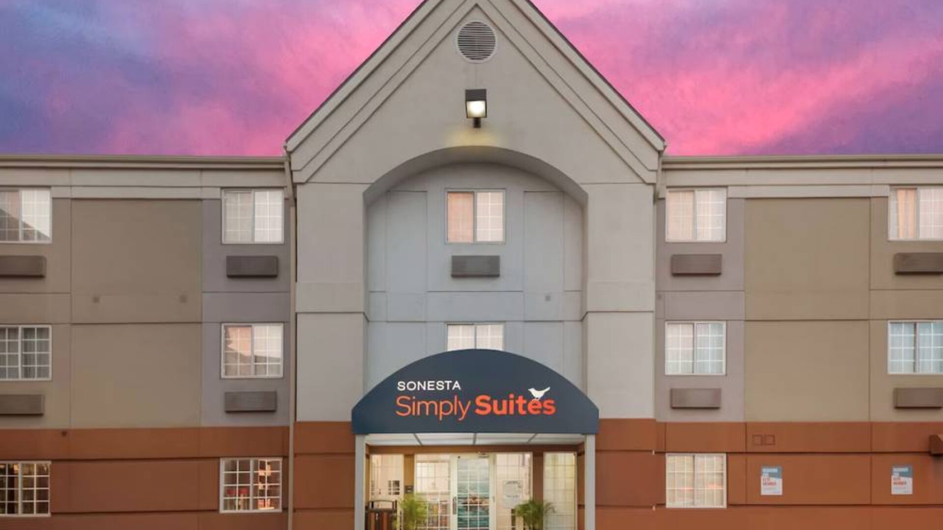 The hotel’s exterior includes potted plants by the front door, above which is the name Sonesta Simply Suites.