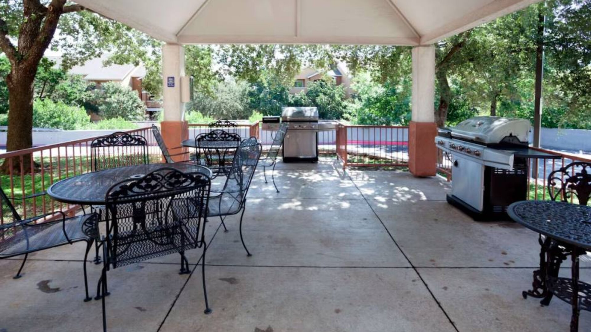 Sonesta Simply Suites Austin The Domain Area’s gazebo has tables and chairs alongside barbecues, and numerous trees nearby.