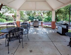 Sonesta Simply Suites Austin The Domain Area’s gazebo has tables and chairs alongside barbecues, and numerous trees nearby.