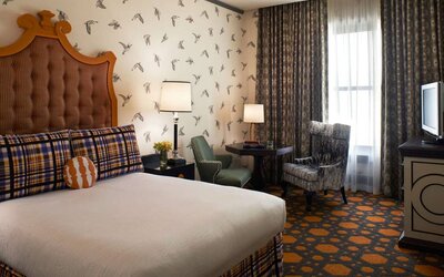 Double bed guest room in Royal Sonesta Portland Downtown, furnished with chairs and a coffee table, window, and a TV.