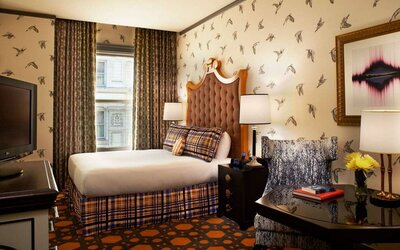 Royal Sonesta Portland Downtown double bed guest room, with chair, coffee table, TV, and window.