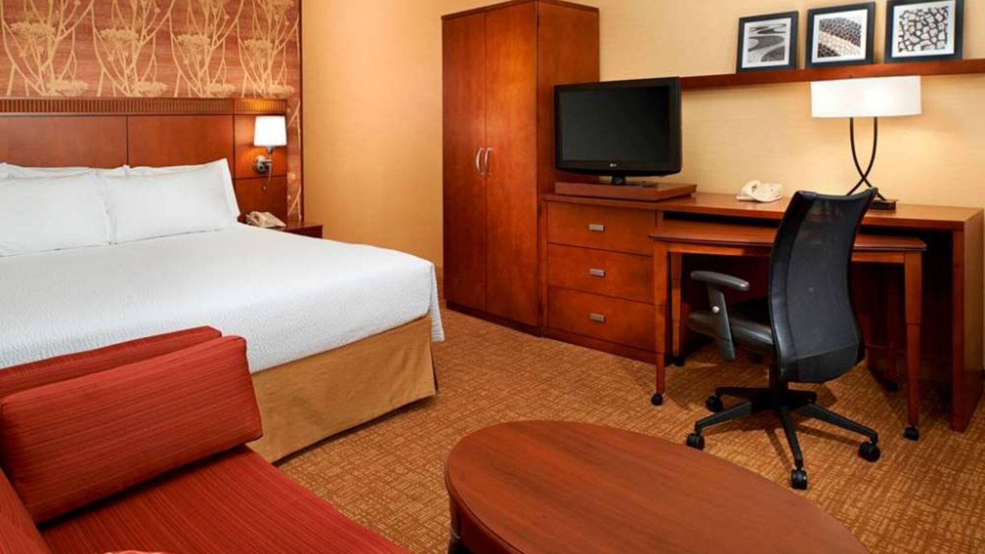 Double bed guest room in Sonesta Select Detroit Auburn Hills, featuring sofa, coffee table, and TV, plus a workspace desk and chair.