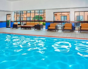 Sonesta Select Detroit Auburn Hills’ indoor pool has armchair and sofa seating by the side, plus large windows.