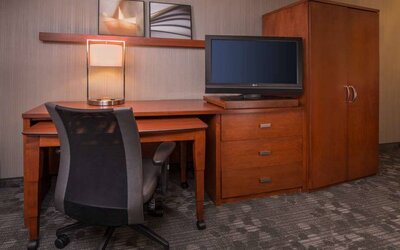Sonesta Select Columbia guest room workspace, featuring desk, chair, and lamp, with a nearby TV.