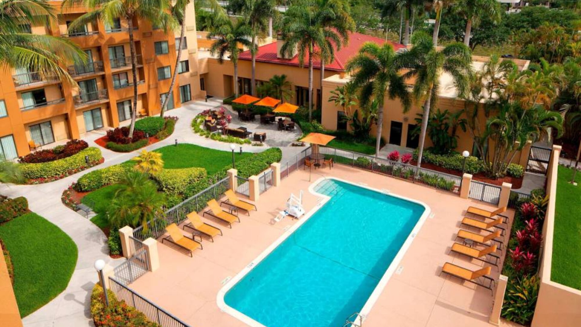 Sonesta Select Boca Raton’s outdoor pool is equipped with a lift, and has sun loungers by the side plus pleasant greenery beyond the fence.