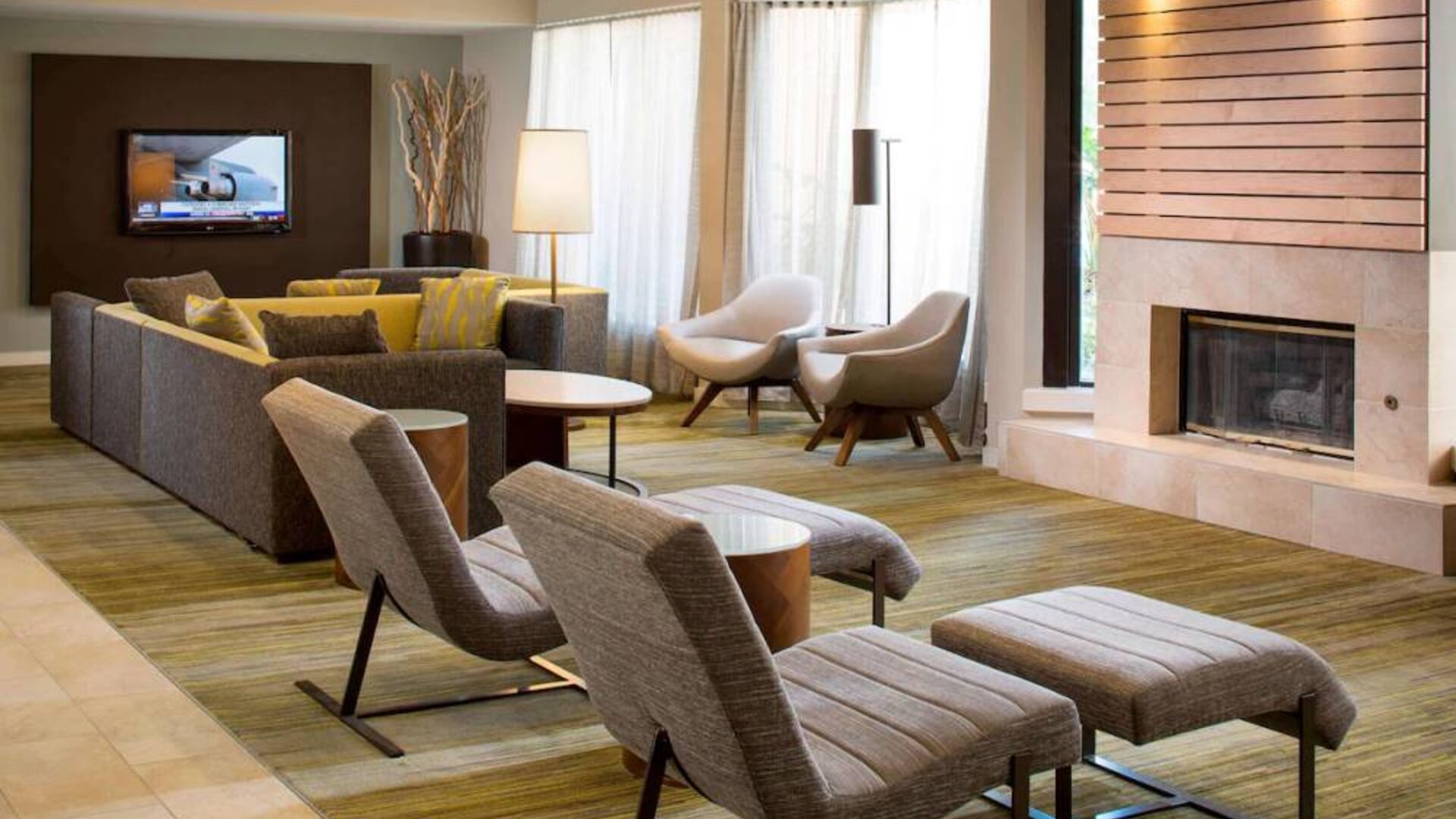 Sonesta Select Boca Raton’s lobby lounge has sofas, chairs, and reclined seats, plus coffee tables, a fireplace, and a wall-mounted television.