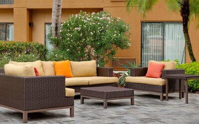 The hotel’s patio is furnished with armchair and sofa seating, plus coffee tables, and is surrounded by greenery.