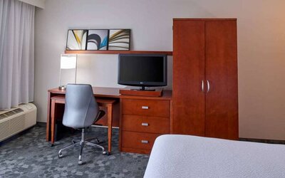 Sonesta Select Indianapolis Carmel guest room workspace, furnished with bed and TV, plus desk, chair, and lamp.