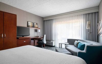 Sonesta Select Phoenix Camelback double bed guest room, furnished with TV, desk, chair, and a sofa.