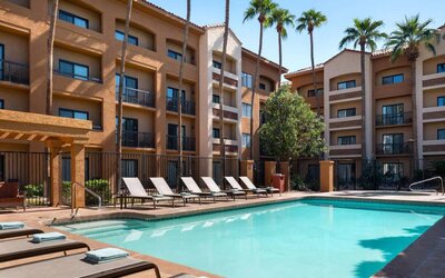 Sonesta Select Phoenix Camelback’s outdoor pool has sun loungers by the side, a shaded area, and tall palm trees.