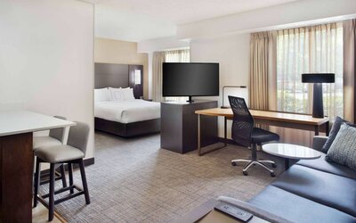 Double bed guest room in Sonesta ES Suites Raleigh Cary, featuring TV and sofa, plus workspace desk, chair, and lamp.