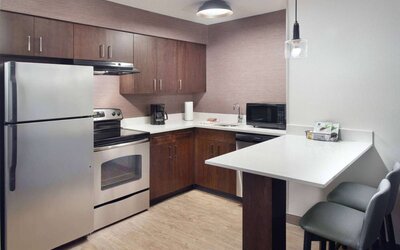 Sonesta ES Suites Raleigh Cary guest room kitchen, fitted with oven, microwave, fridge-freezer, and sink.