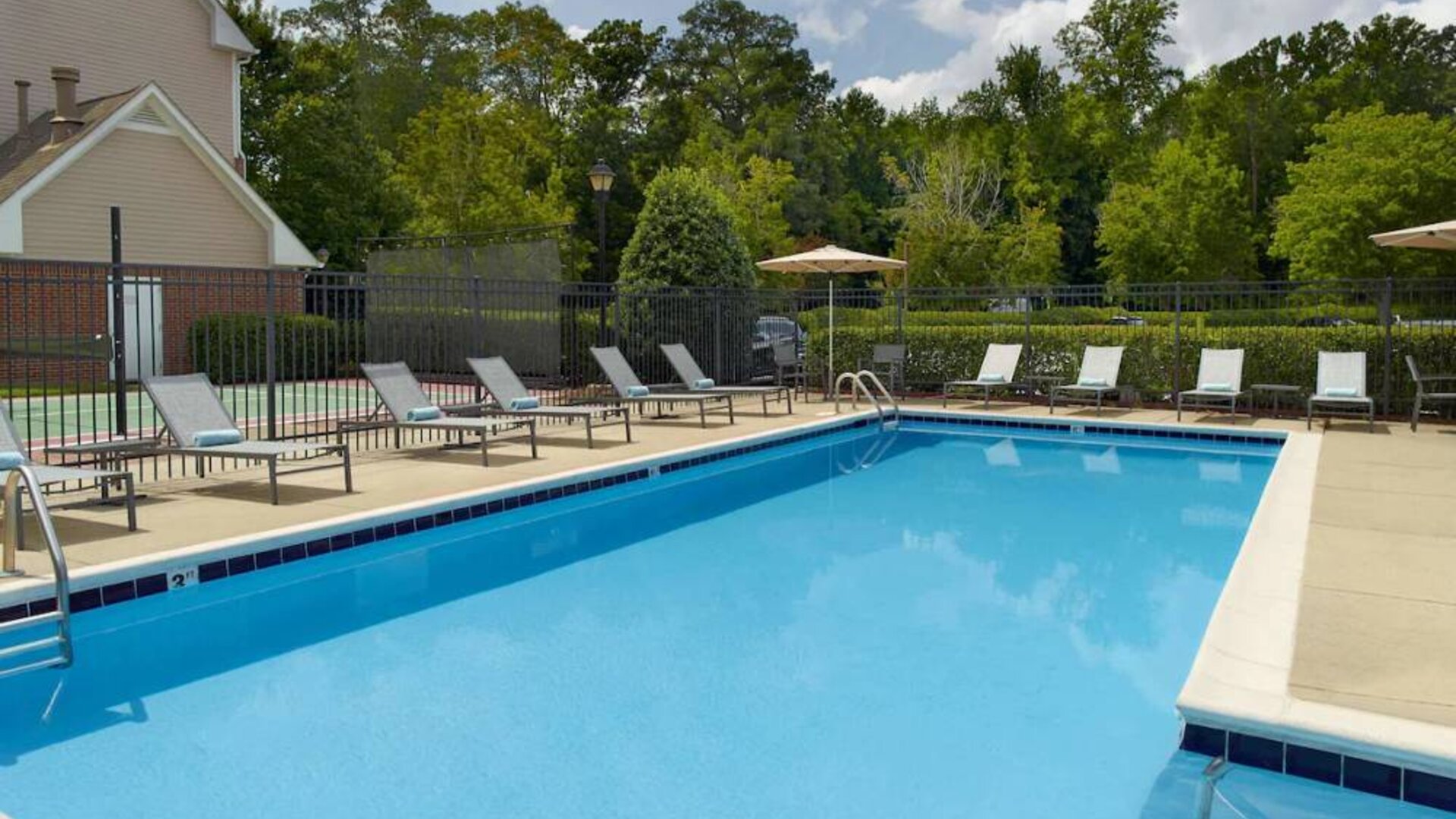Sonesta ES Suites Raleigh Cary’s outdoor pool has shaded tables and chairs, and numerous sun loungers, by the side.