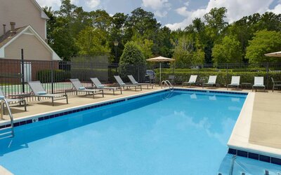 Sonesta ES Suites Raleigh Cary’s outdoor pool has shaded tables and chairs, and numerous sun loungers, by the side.