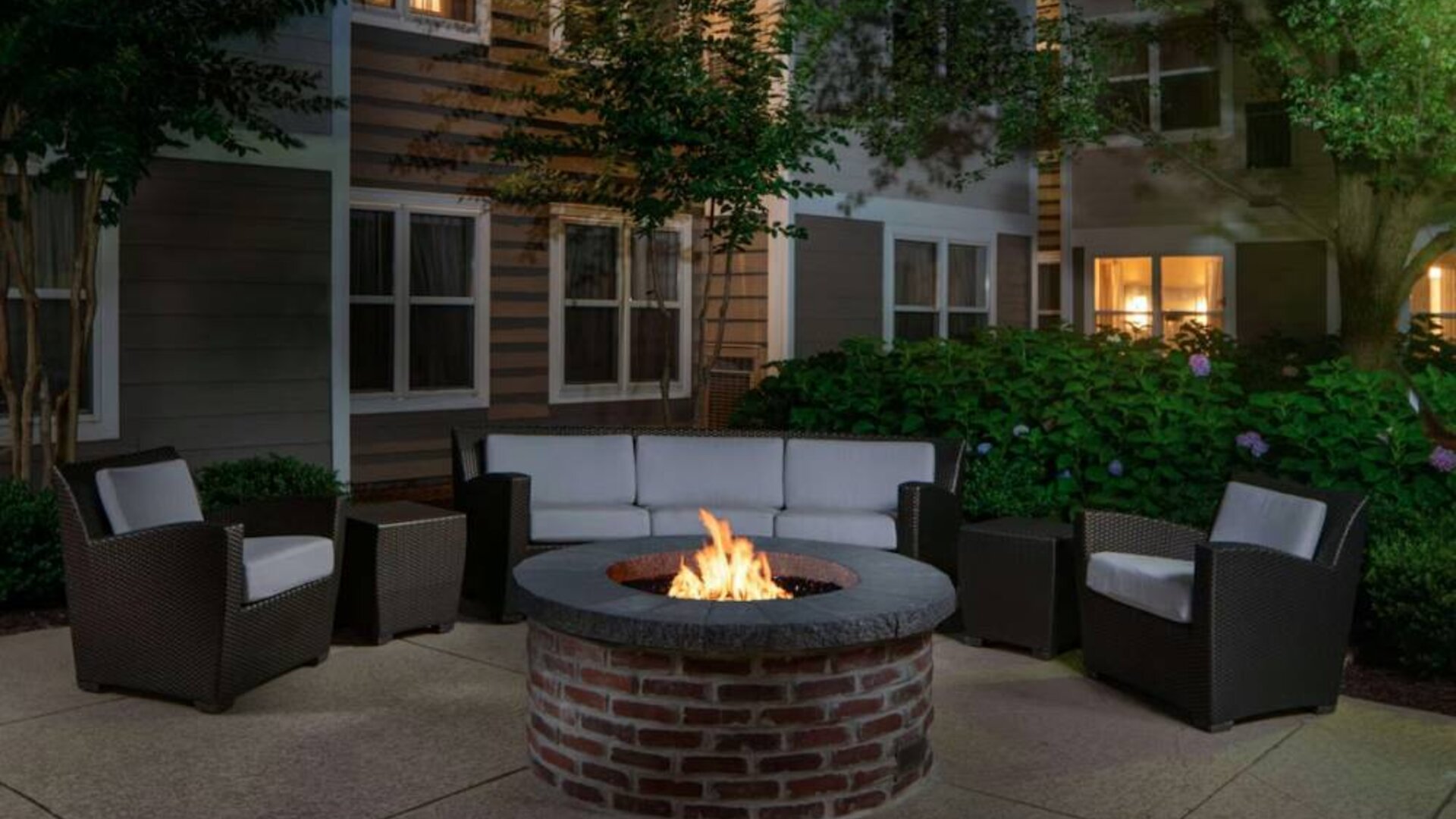 Sonesta ES Suites Fairfax Fair Lakes’ fire pit has armchairs, coffee tables, and a sofa where guests can relax and socialize.