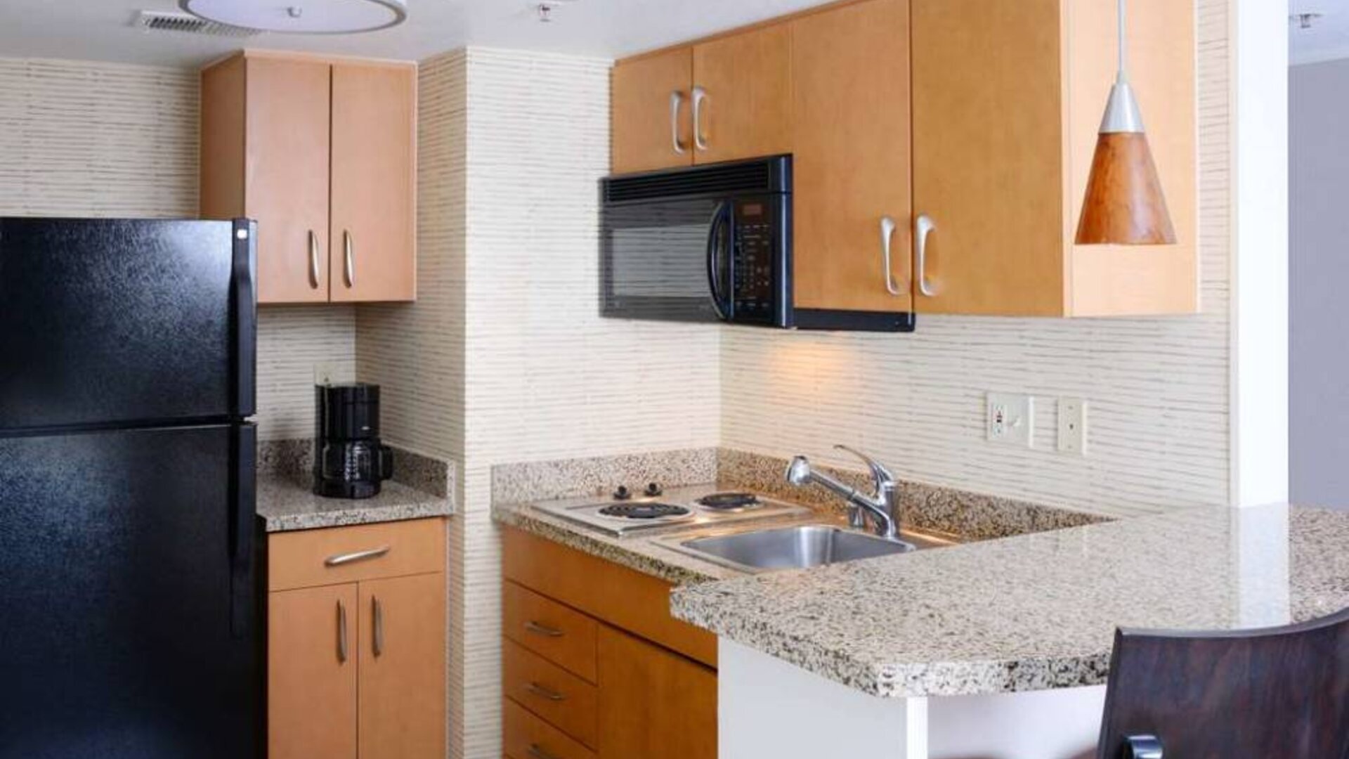 Sonesta ES Suites Dallas Medical Market Center guest room kitchen, with microwave, fridge-freezer, and hob.