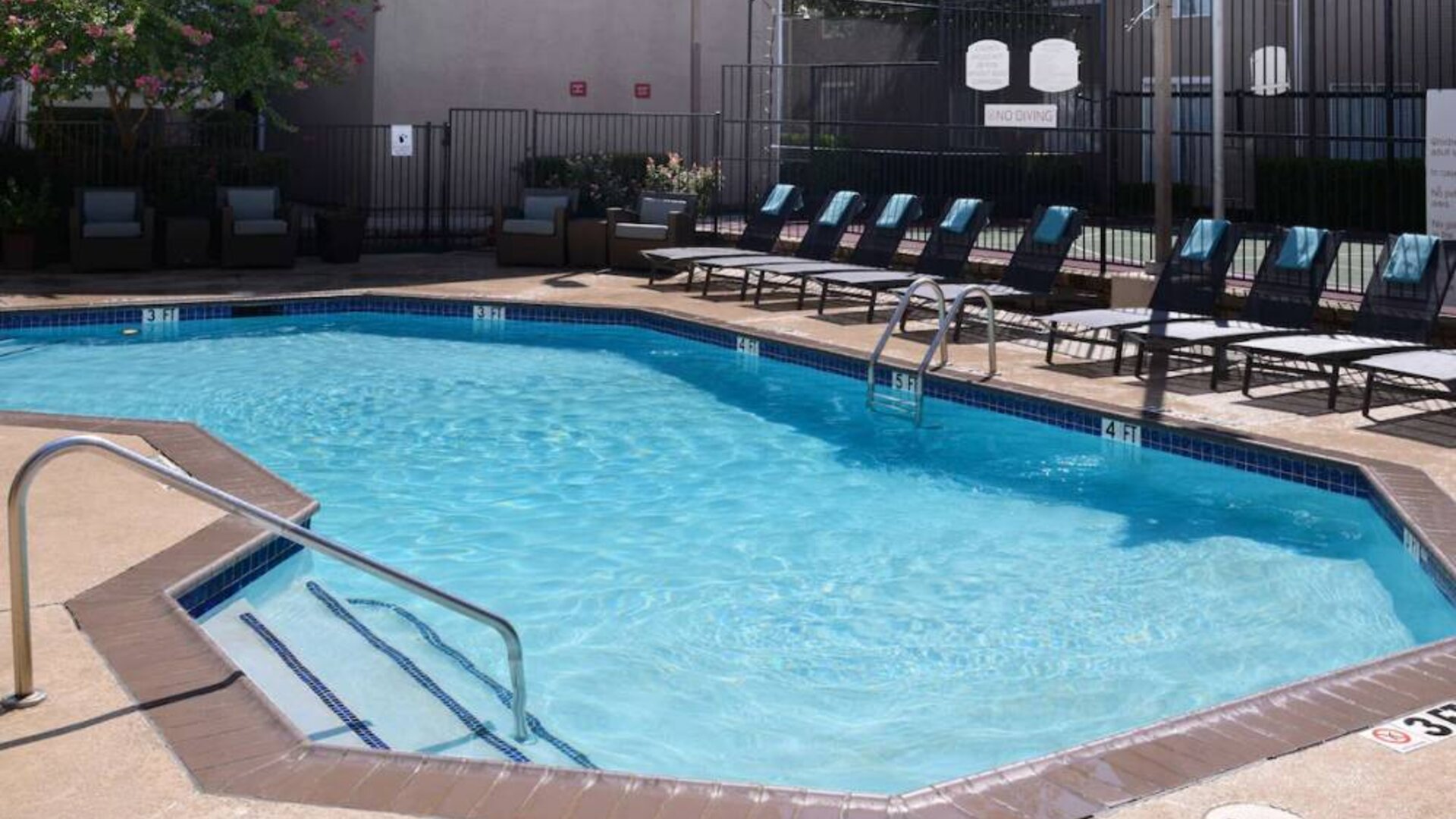 Sonesta ES Suites Dallas Medical Market Center’s outdoor pool has sun loungers as well as armchairs and coffee tables by its side.