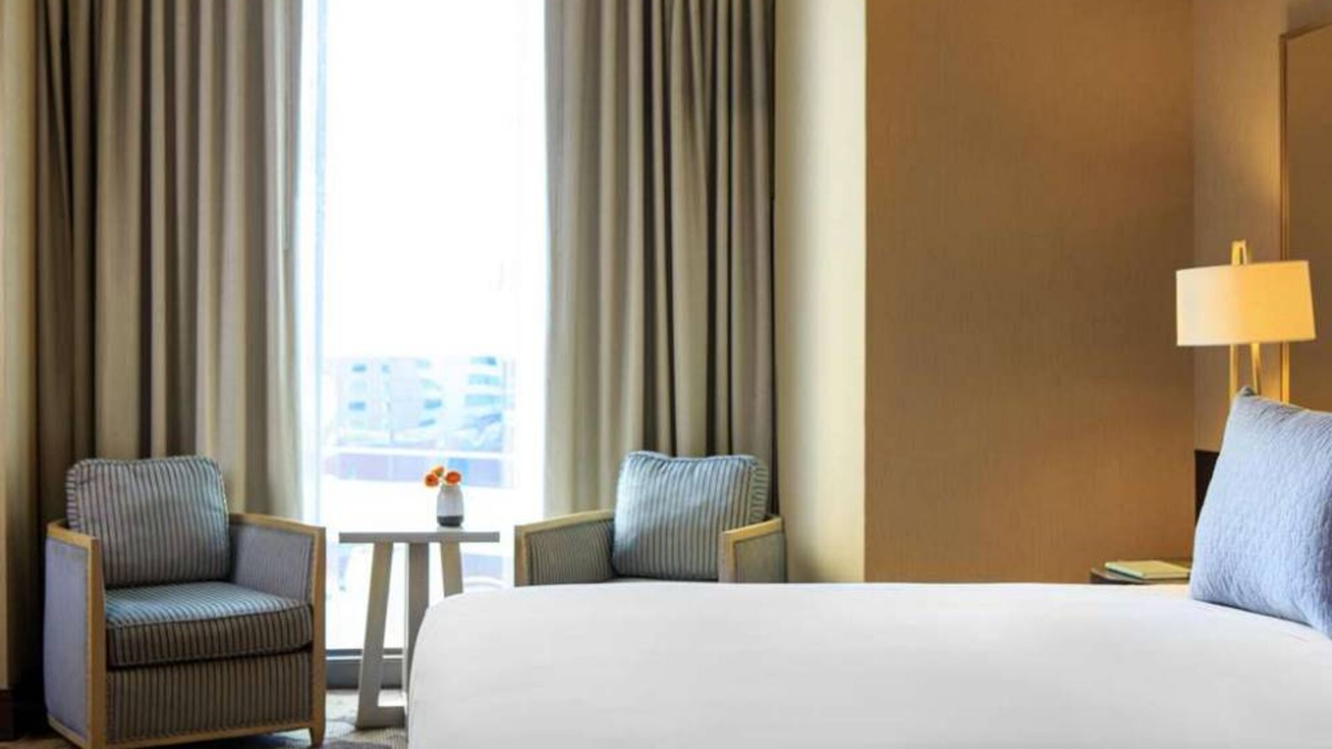 Double bed guest room in Royal Sonesta Chicago River North, including coffee table, two chairs, and a large window.