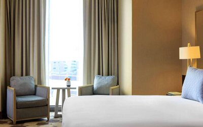 Double bed guest room in Royal Sonesta Chicago River North, including coffee table, two chairs, and a large window.