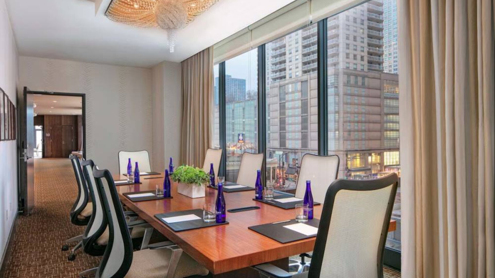 Hotel meeting room, with long wooden table, eight swivel chairs, and floor-to-ceiling windows.