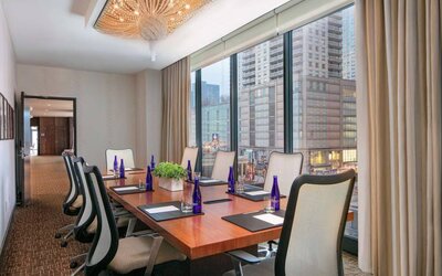 Hotel meeting room, with long wooden table, eight swivel chairs, and floor-to-ceiling windows.