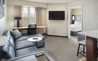 Double bed guest room living area in Sonesta ES Suites Raleigh Durham Airport Morrisville, with sofa, window, and TV.