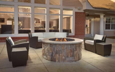 Fire pit surrounded by armchair and sofa seating, plus coffee tables, at Sonesta ES Suites Raleigh Durham Airport Morrisville.