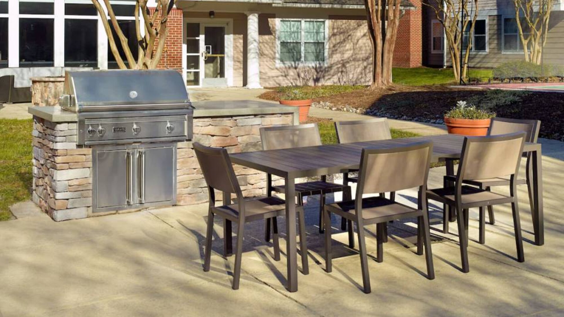 Barbecue with table and six chairs nearby at Sonesta ES Suites Raleigh Durham Airport Morrisville.