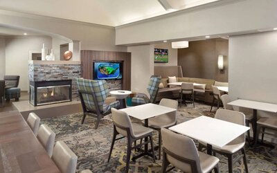 Lobby lounge furnished with sofa seating, tables and chairs, a fireplace and TV, at Sonesta ES Suites Raleigh Durham Airport Morrisville.