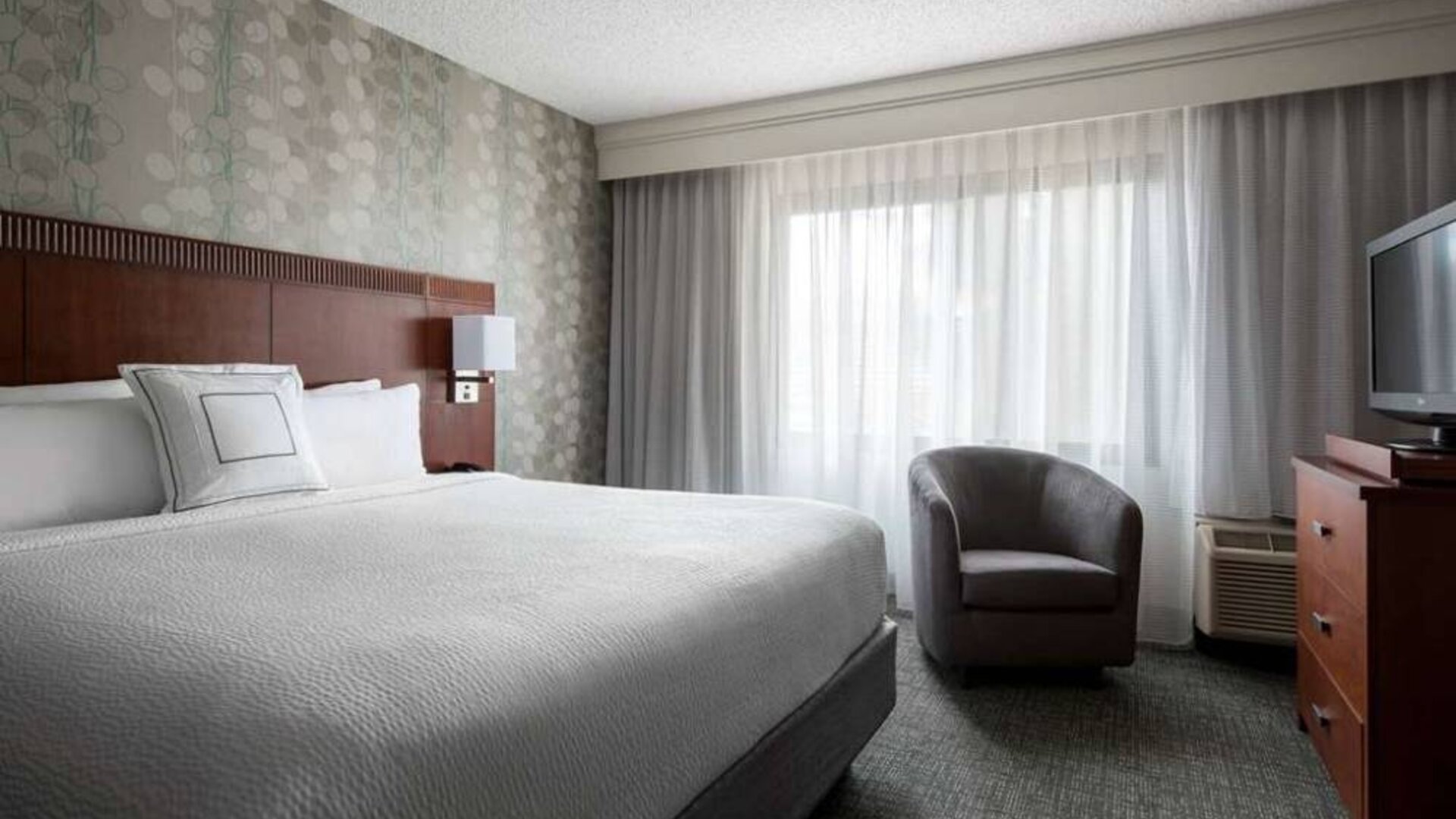 Double bed guest room in Sonesta Select Los Angeles LAX El Segundo, featuring armchair, window, and TV.