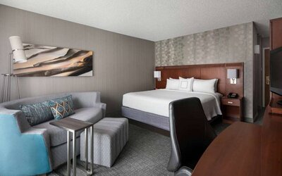 Sonesta Select Los Angeles LAX El Segundo double bed guest room including TV, chair, and sofa.