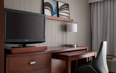 Guest room workspace in Sonesta Select Los Angeles LAX El Segundo, with chair, desk, lamp, and TV.