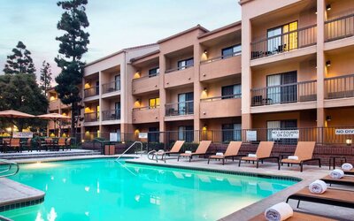 Sonesta Select Los Angeles LAX El Segundo’s outdoor pool has shaded tables and chairs, as well as sun loungers, by the side.