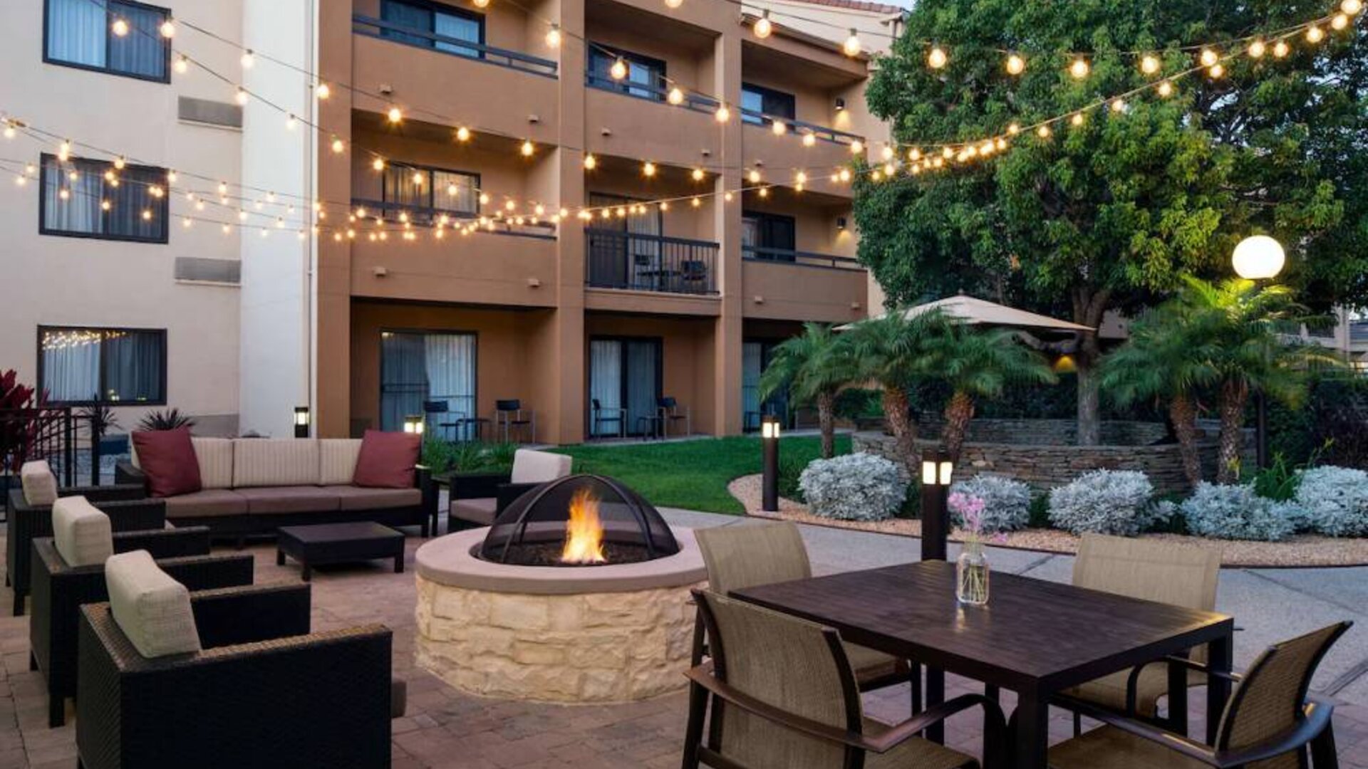 Fire pit with armchairs next to it, and more seating nearby, at Sonesta Select Los Angeles LAX El Segundo.
