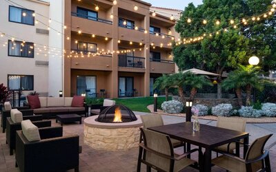 Fire pit with armchairs next to it, and more seating nearby, at Sonesta Select Los Angeles LAX El Segundo.