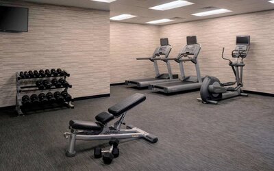 Fitness center furnished with free weights, assorted exercise machines, and a TV at Sonesta Select Kansas City South Overland Park.
