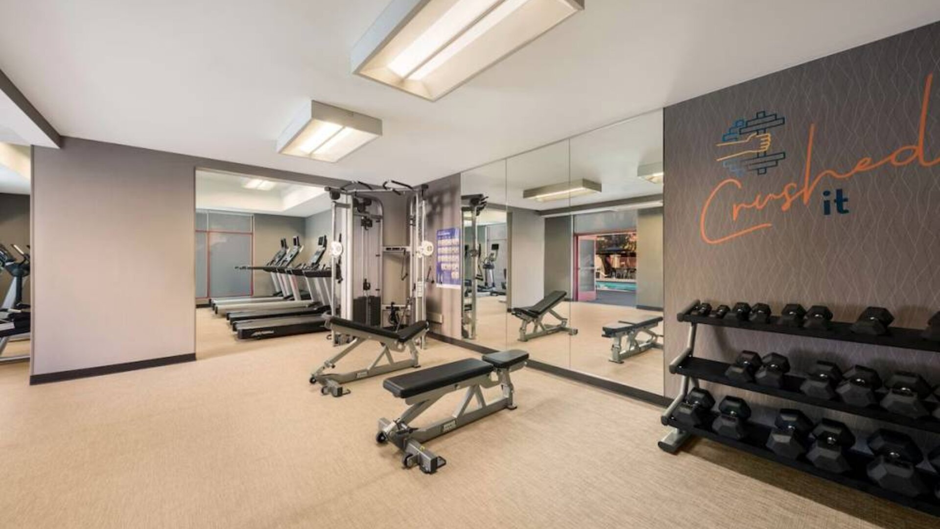Sonesta Select Pleasant Hill’s fitness center features free weights, a mirrored wall, and various exercise machines.