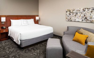 Double bed guest room in Sonesta Select Miami Lakes, featuring art on the wall and a sofa.