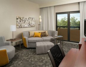 Guest room living area in Sonesta Select Miami Lakes, including sofa, chair, and TV.
