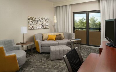 Guest room living area in Sonesta Select Miami Lakes, including sofa, chair, and TV.