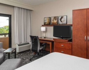 Sonesta Select Miami Lakes’ double bed guest room, with TV and a workspace desk, chair, and lamp.